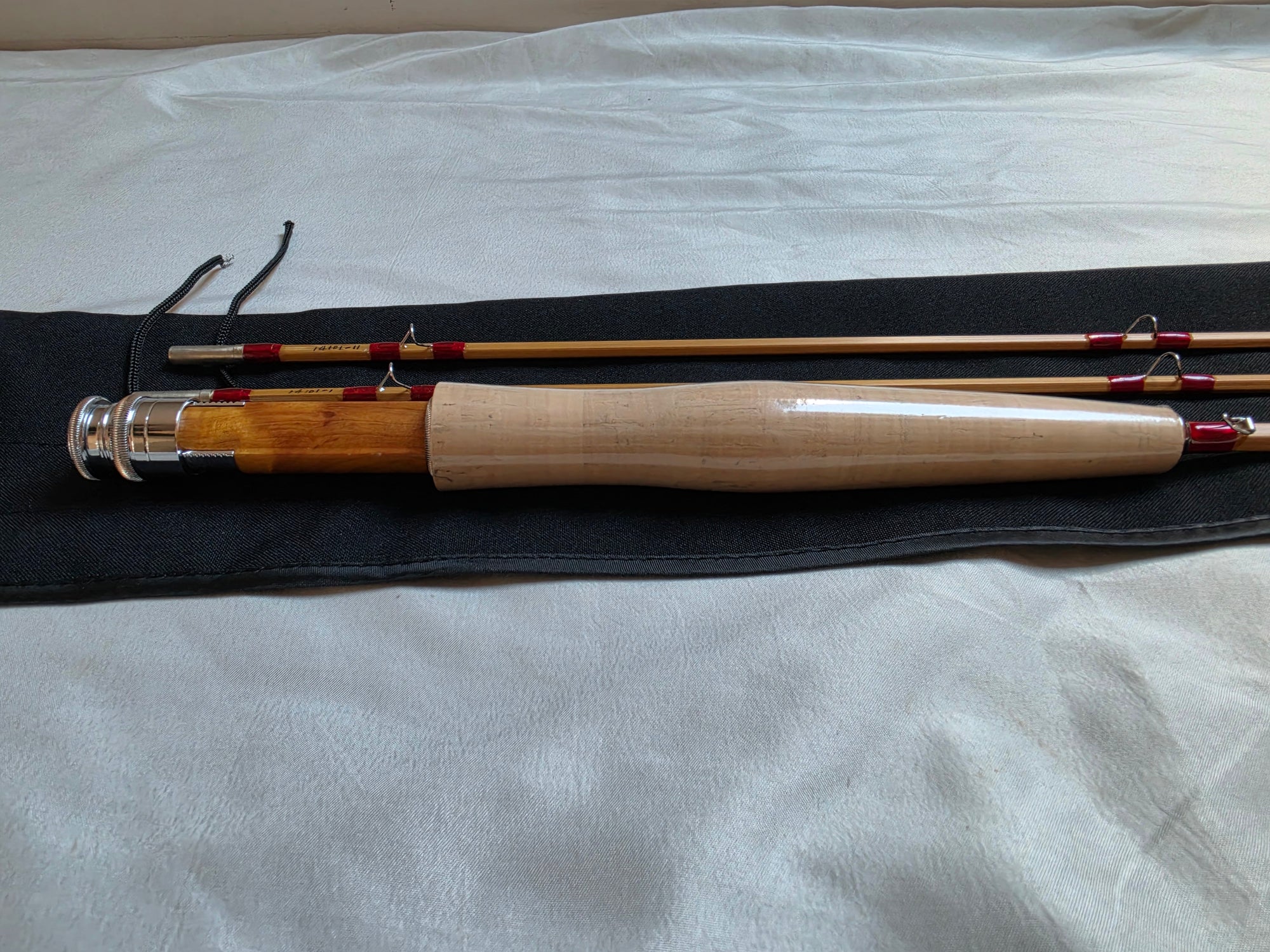 Dickerson 7613 bamboo fly rod grip and sections laid out on black cloth rod bag